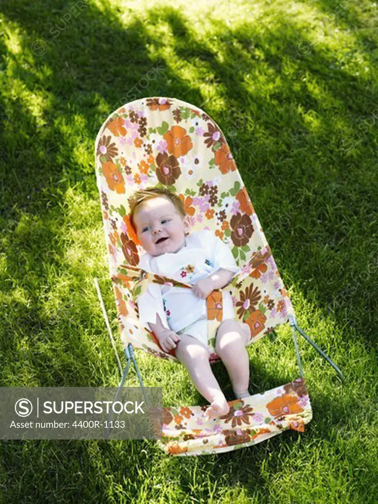 A baby in a bouncy chair in the garden, Sweden.