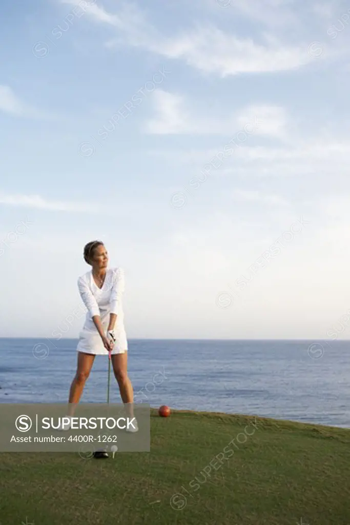 A woman playing golf by the sea, Gran Canaria, Spain.