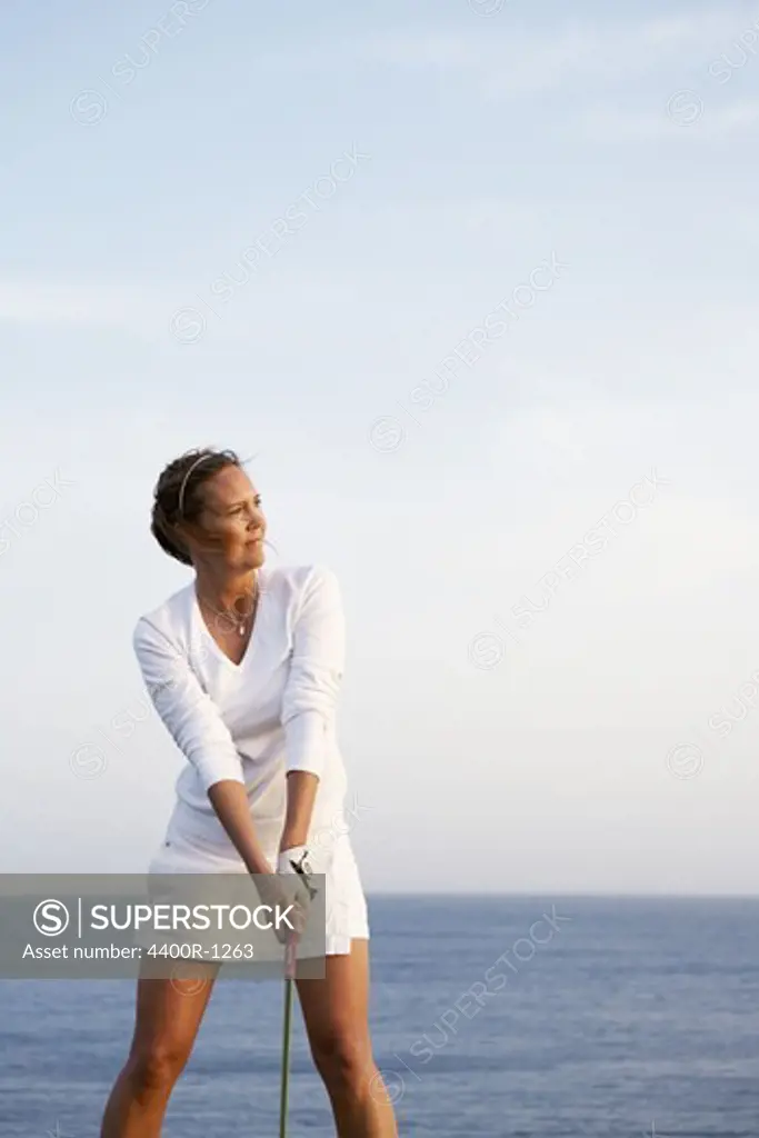 A woman playing golf by the sea, Gran Canaria, Spain.