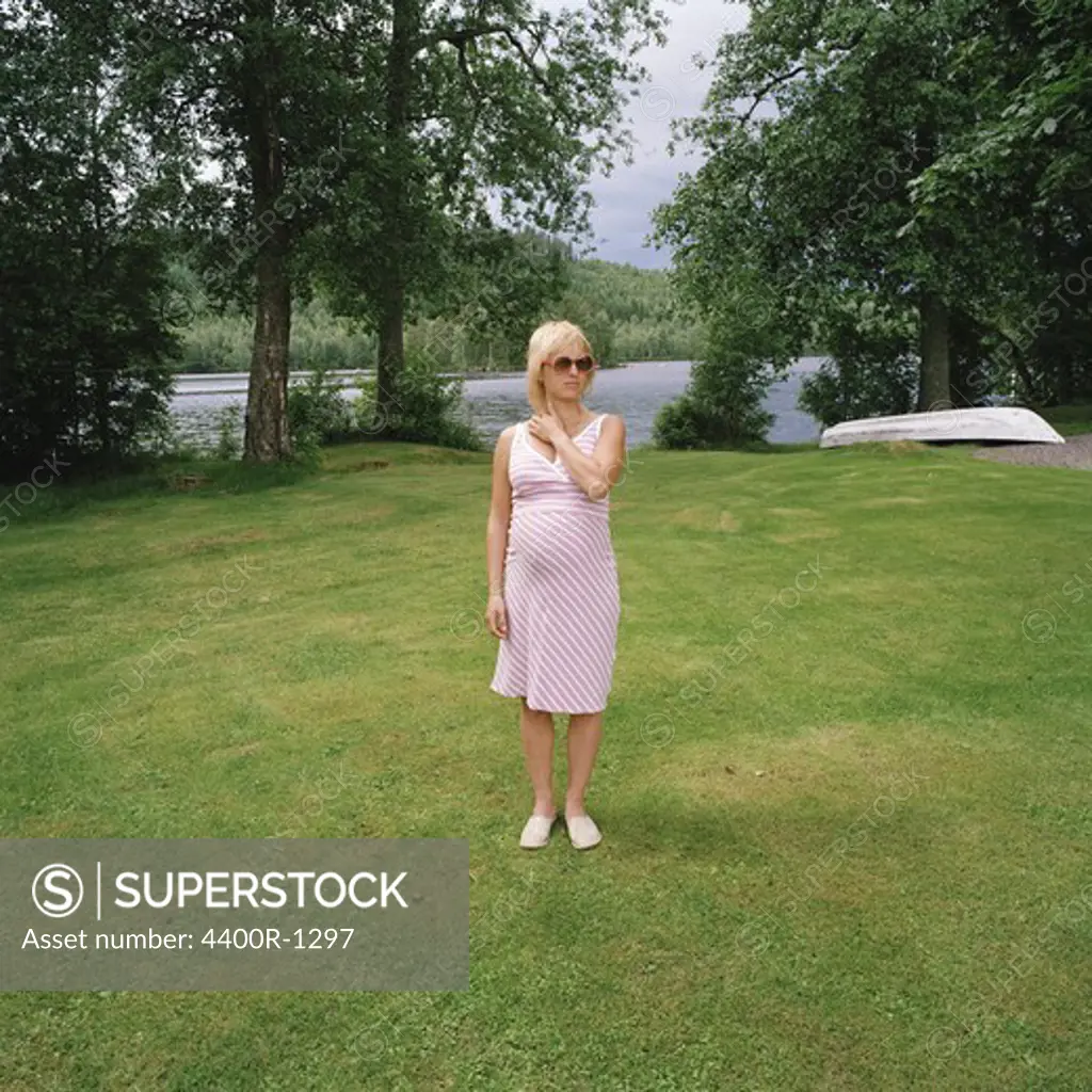 A pregnant woman standing on a lawn, Sweden.