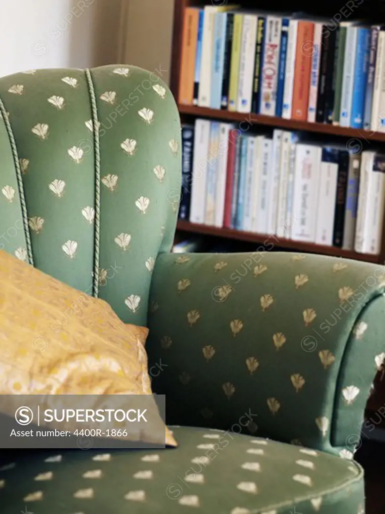 A green armchair by a bookshelf, Sweden.
