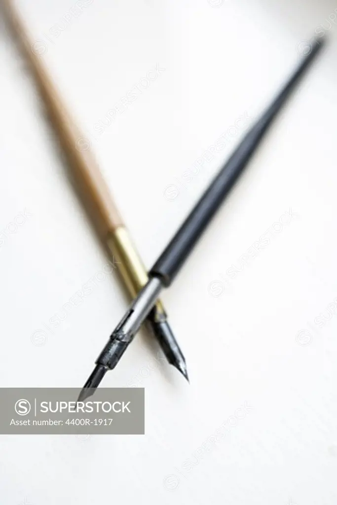 A paintbrush and a pencil, close-up.
