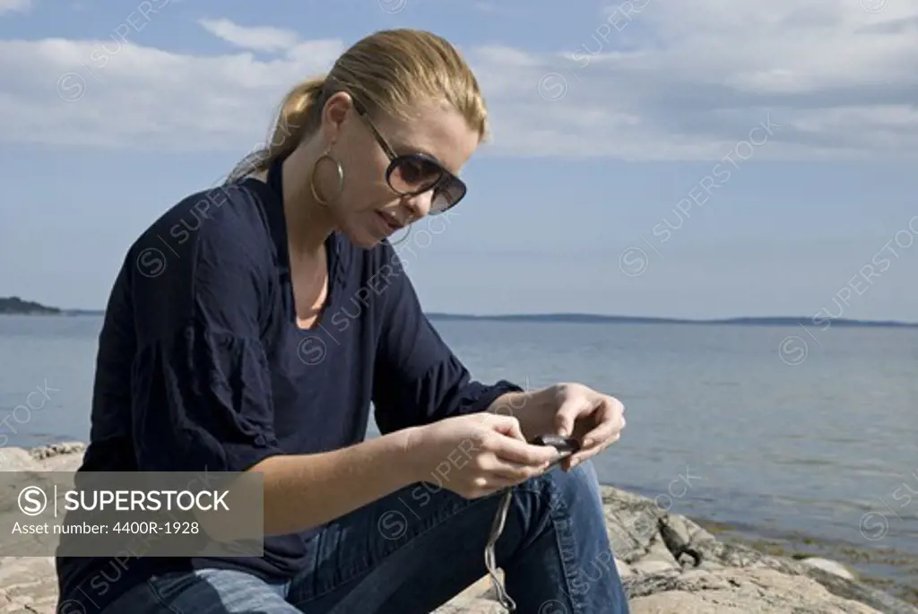 A young woman sitting by the sea, Sweden.