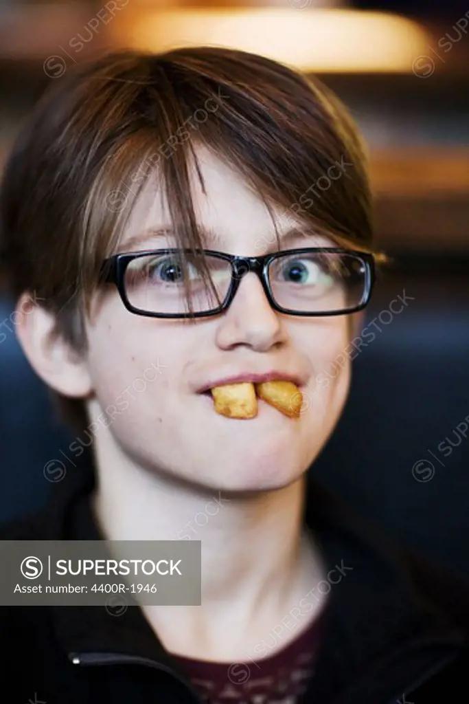 Portrait of a boy with frensh fries in his mouth, Sweden.