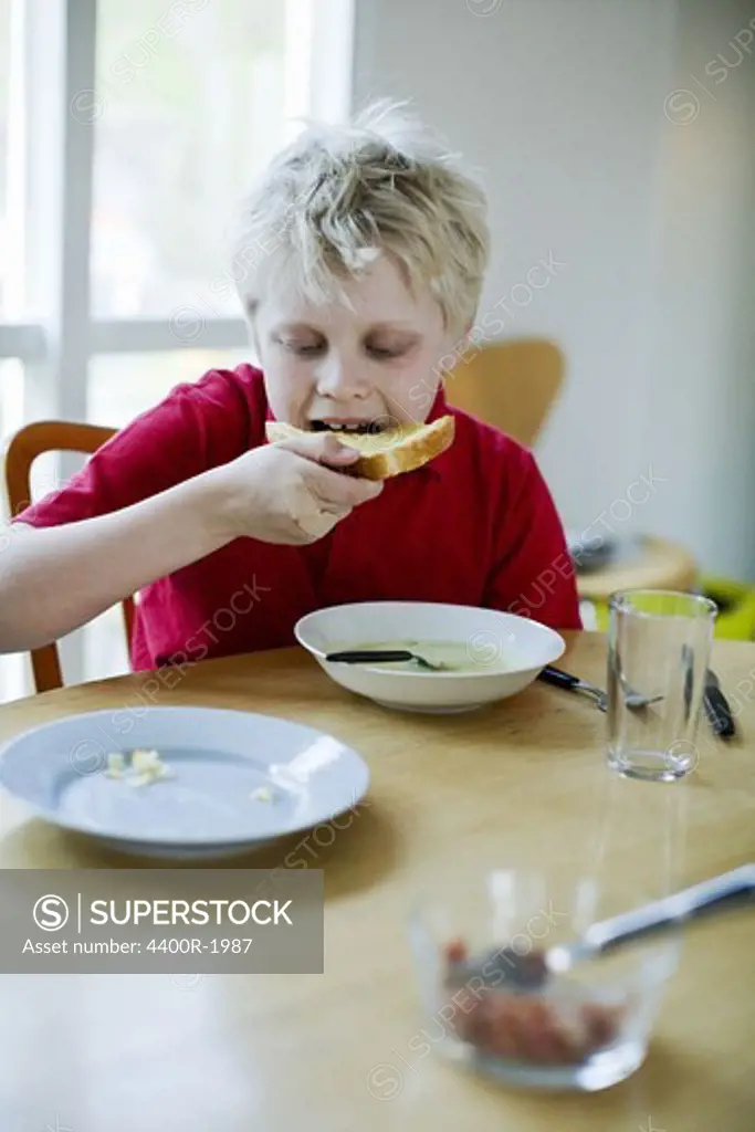 A boy having bread and soup for dinner, Sweden.