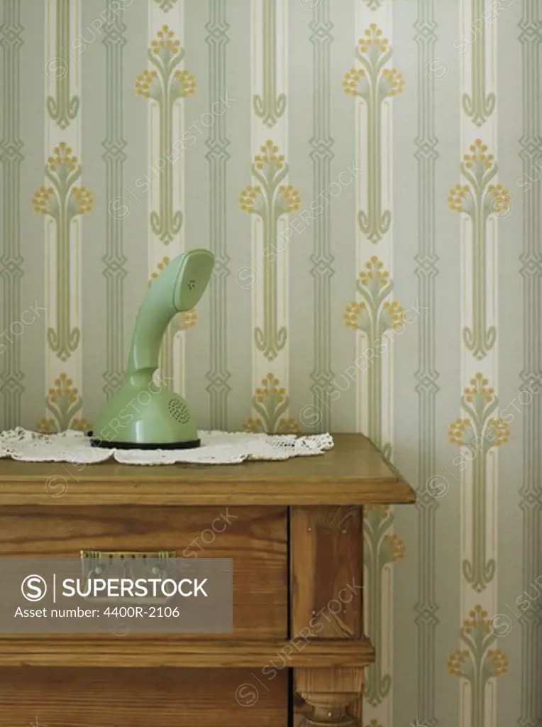 Vintage phone in front of patterned wallpaper