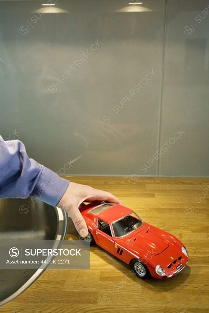 A man holding a toy car on the sink unit, Sweden.