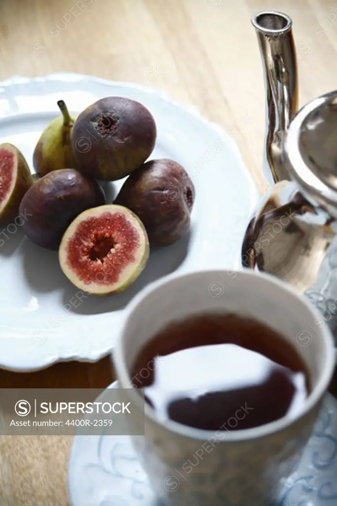 A cup of tea and figs on a plate, close-up.