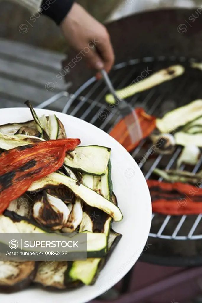 The hand of a person grilling vegetables.