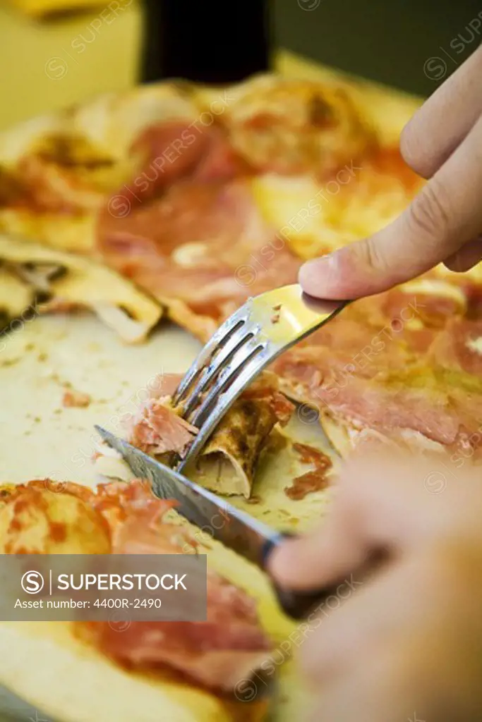 The hands of a boy eating pizza.