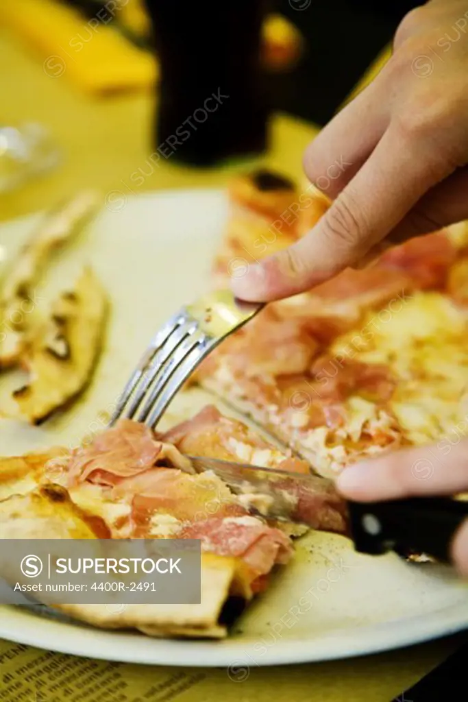 The hands of a boy eating pizza.