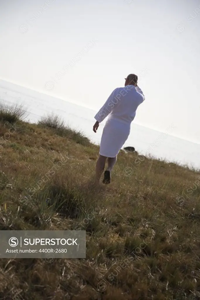 Man on a beach dressed in a bathrobe, Sweden.