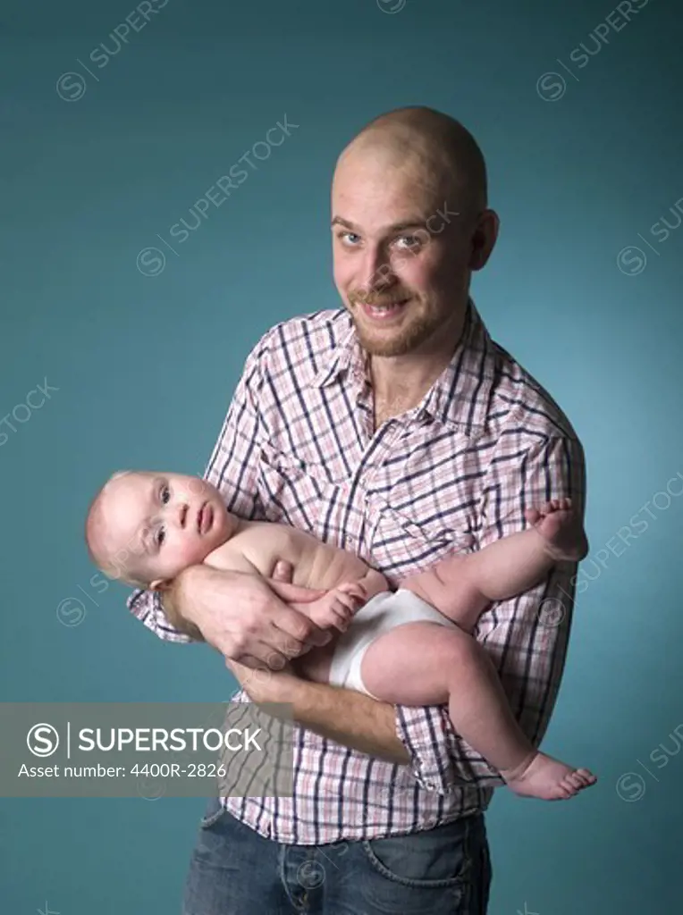 Father and baby boy against turquoise background.