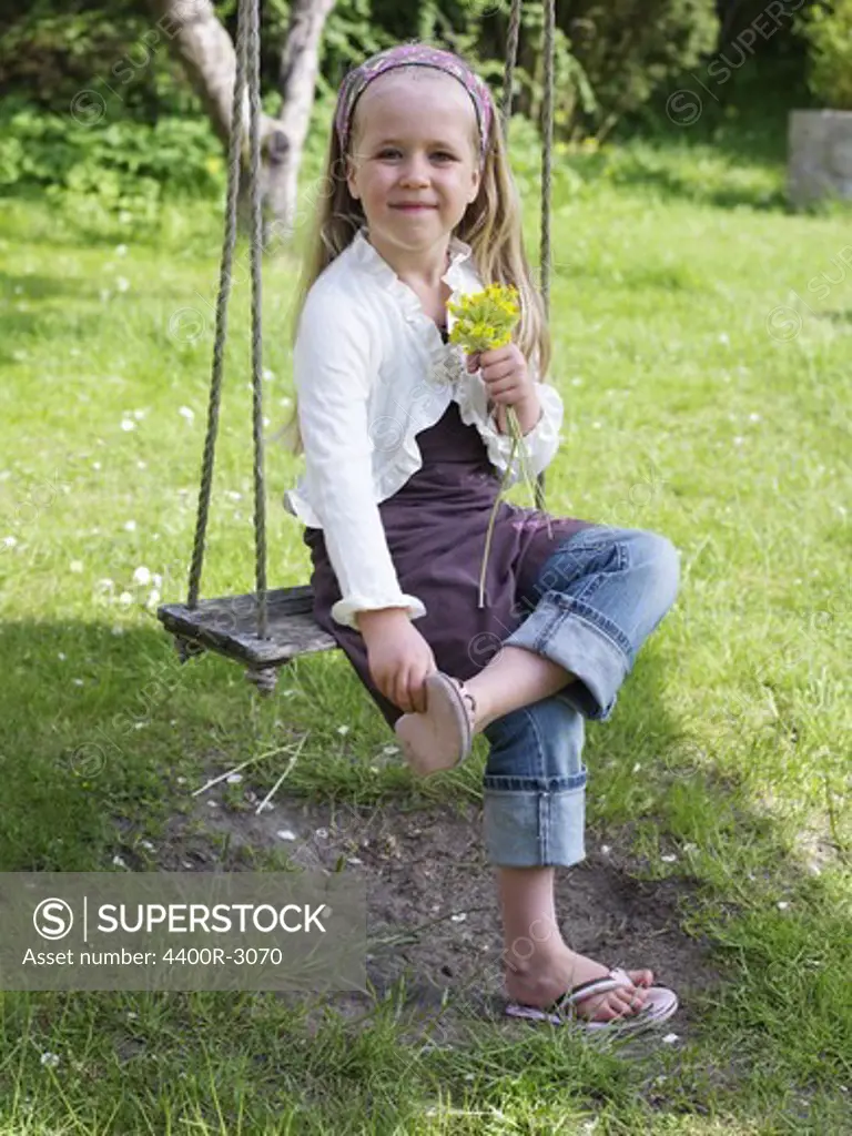 A smiling girl sitting in a swing, Skane, Sweden.