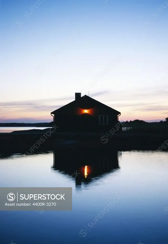 Boathouse reflected in the surface of water, Sweden.