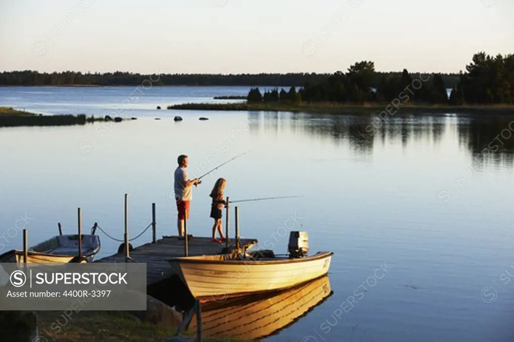 Father and daughter fishing from a jetty, Sweden.