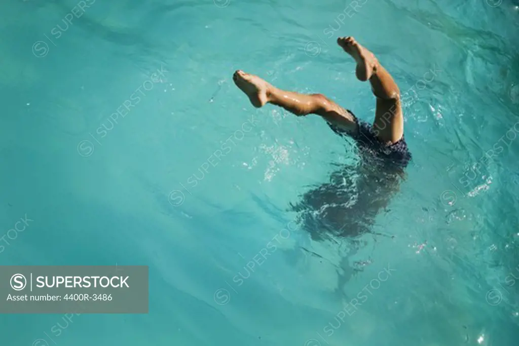 Boy diving into turquoise water, Sweden.