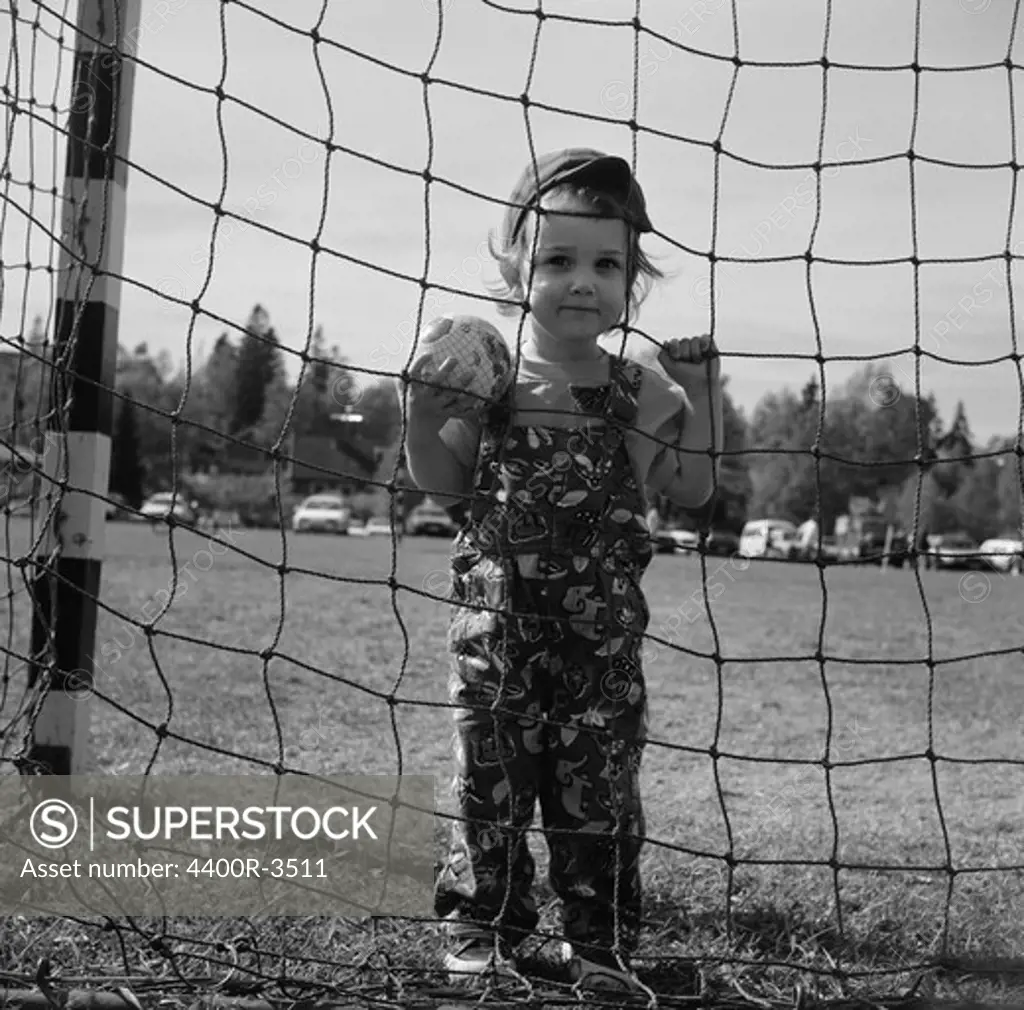 Boy looking through net on football field