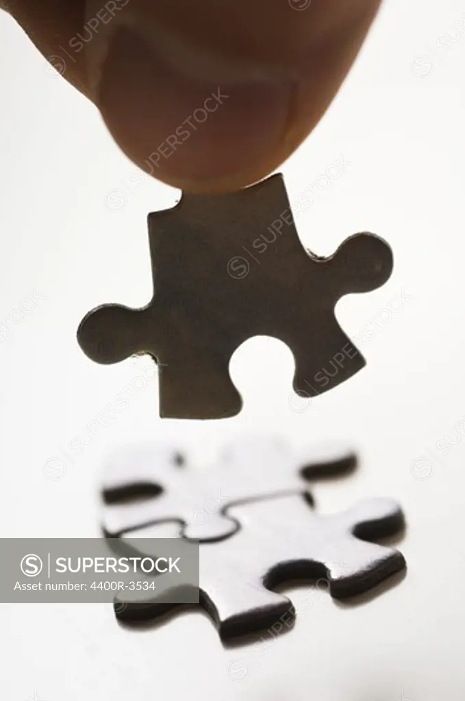 Human hand holding jigsaw piece, close-up