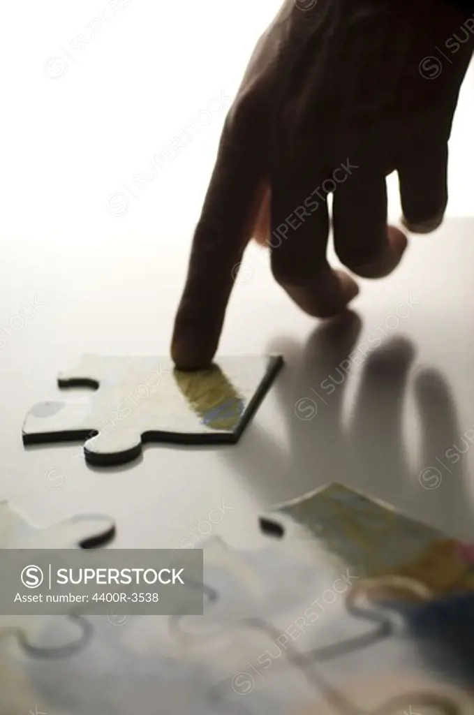 Human hand joining jigsaw pieces, close-up