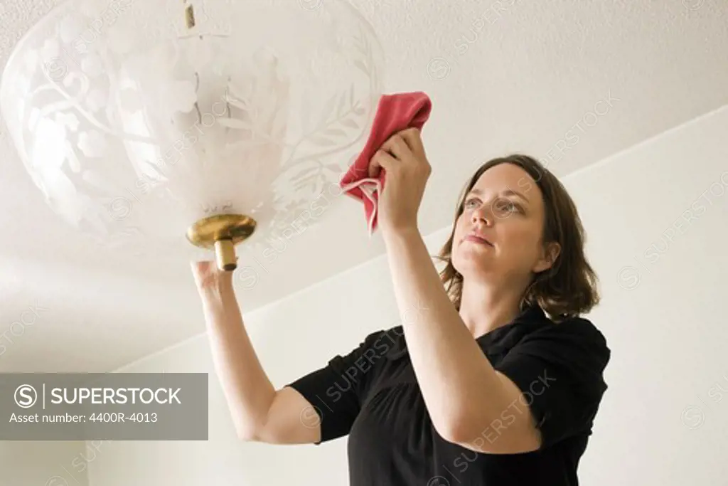 Woman dusting a lamp, Sweden.