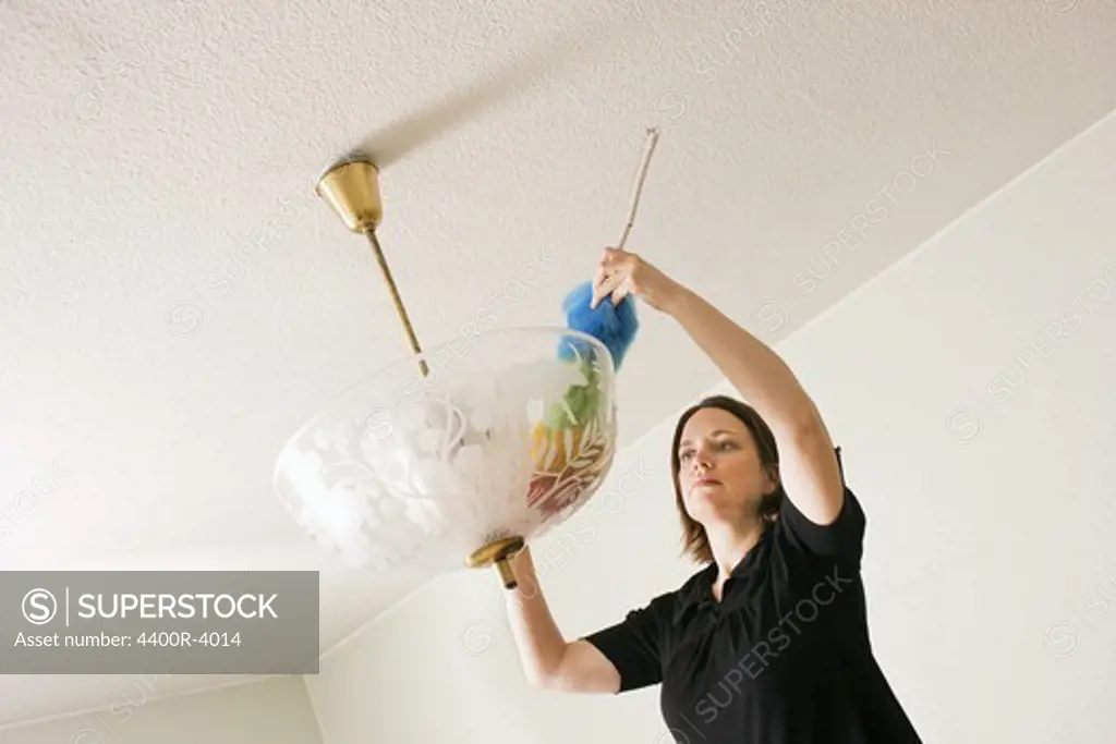 Woman dusting a lamp, Sweden.