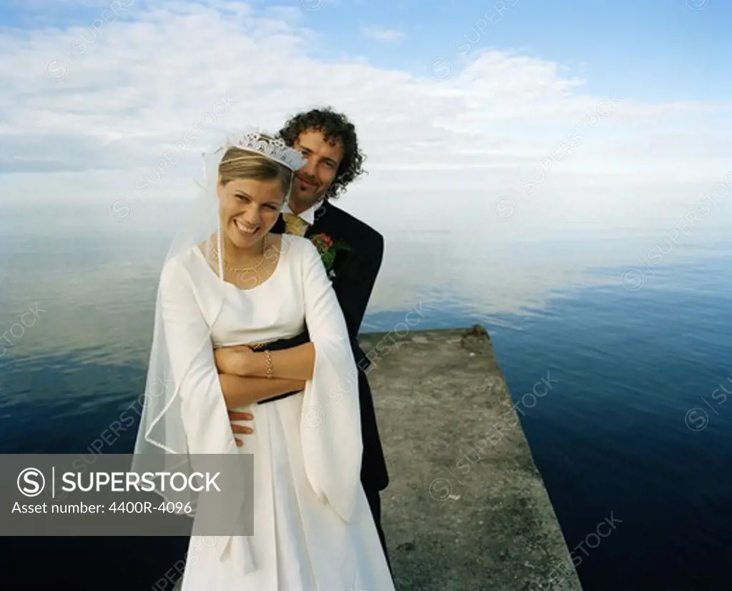 Scandinavia, Sweden, Oland, Groom and bride embracing on jetty, smiling, portrait