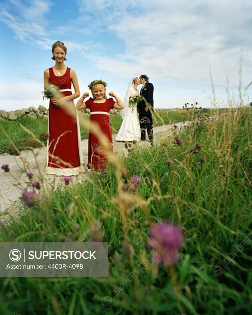 Scandinavia, Sweden, Oland, Bridesmaid and flower girl with bride and groom kissing in background