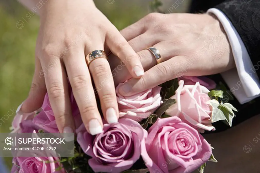 Bride and groom with wedding rings on top of bouquet