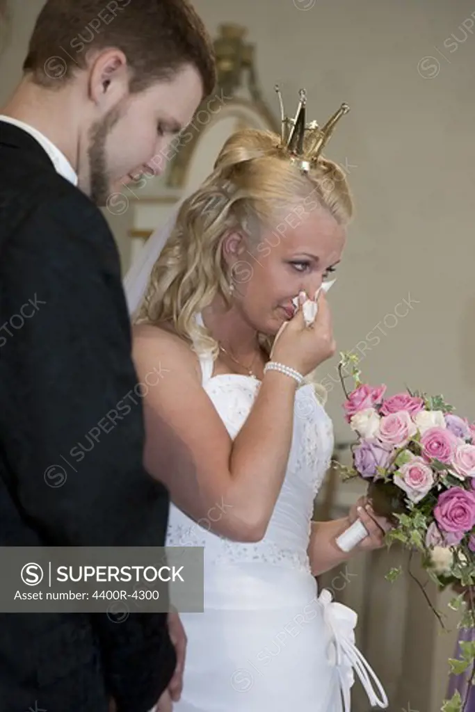 Bride standing with groom blowing her nose