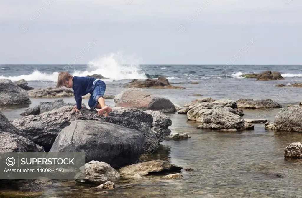 Boy climbing on rocks at beach