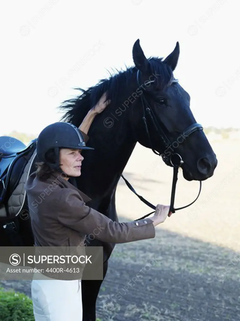 Woman standing by horse holding reins