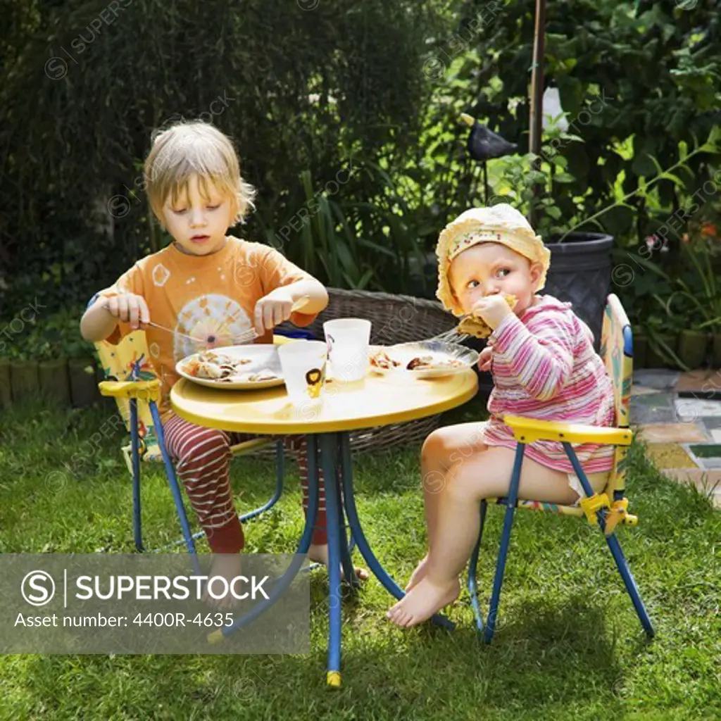 Boy and girl eating pancake in garden