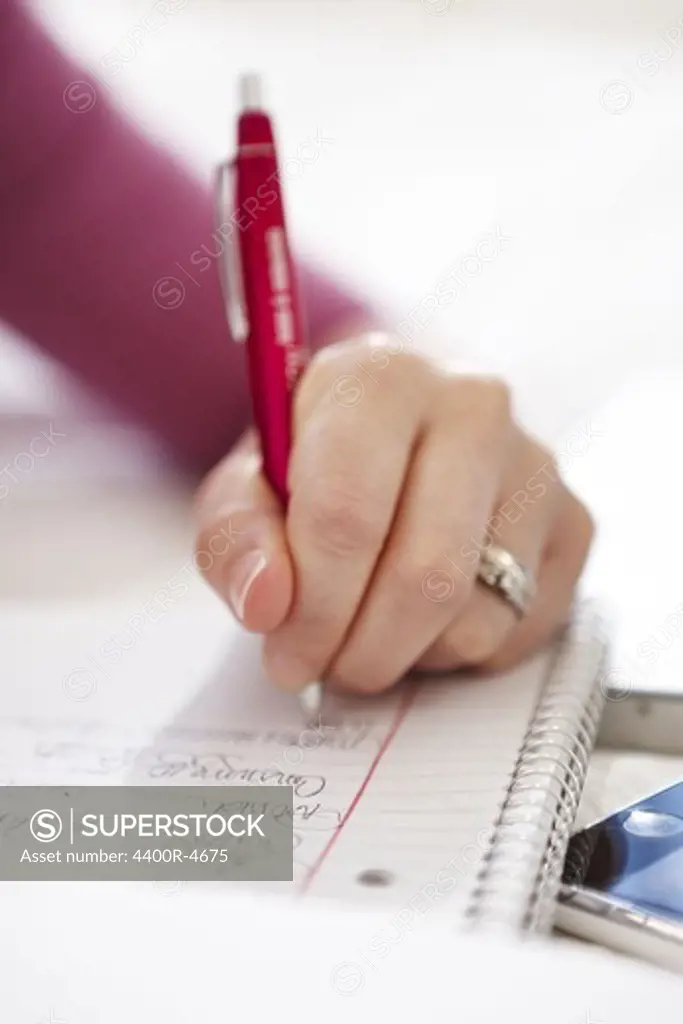 Close-up of womans hand writing on notebook