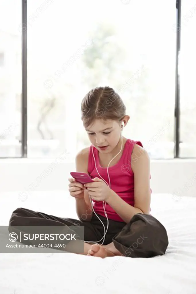 Girl listening MP3 player on bed