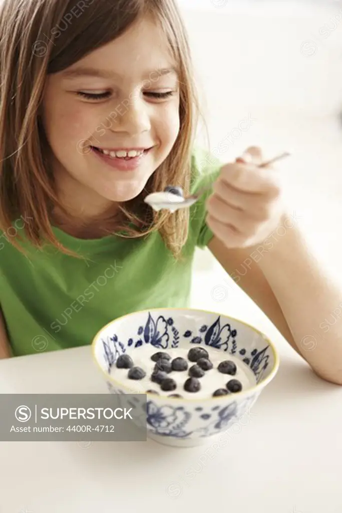 Girl eating yoghurt with blueberry