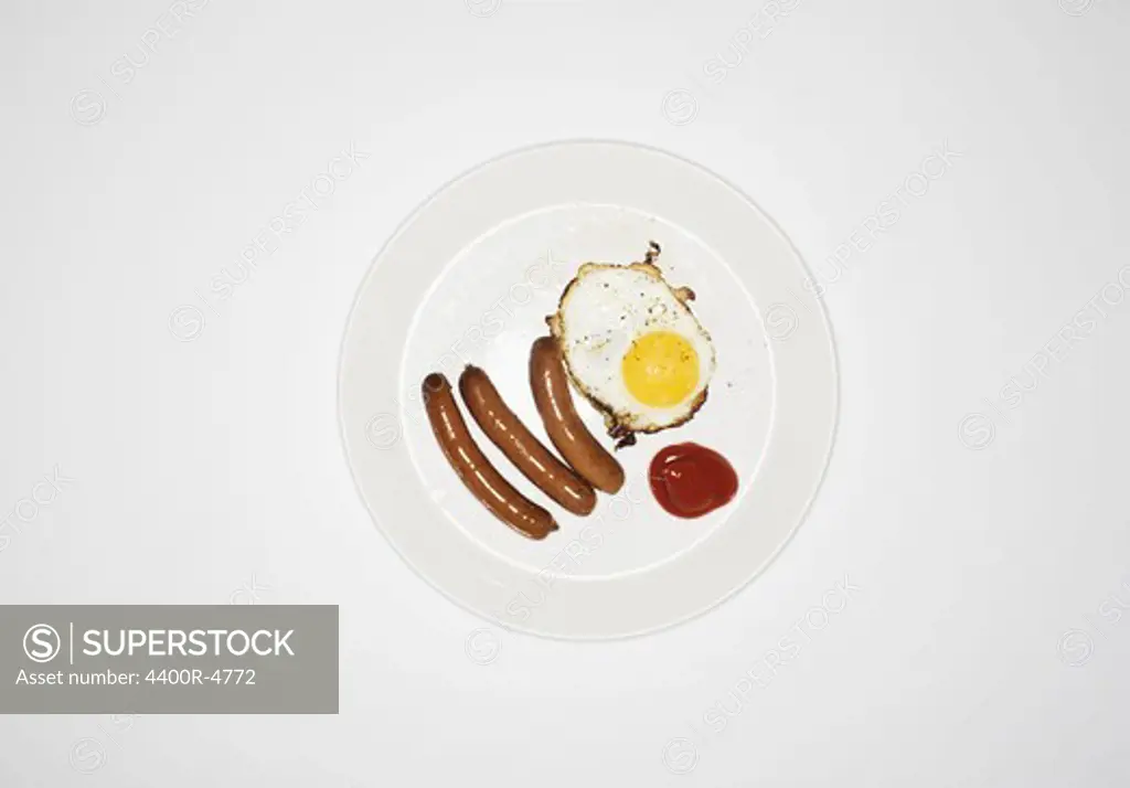 Plate of sausage and fried egg on white background