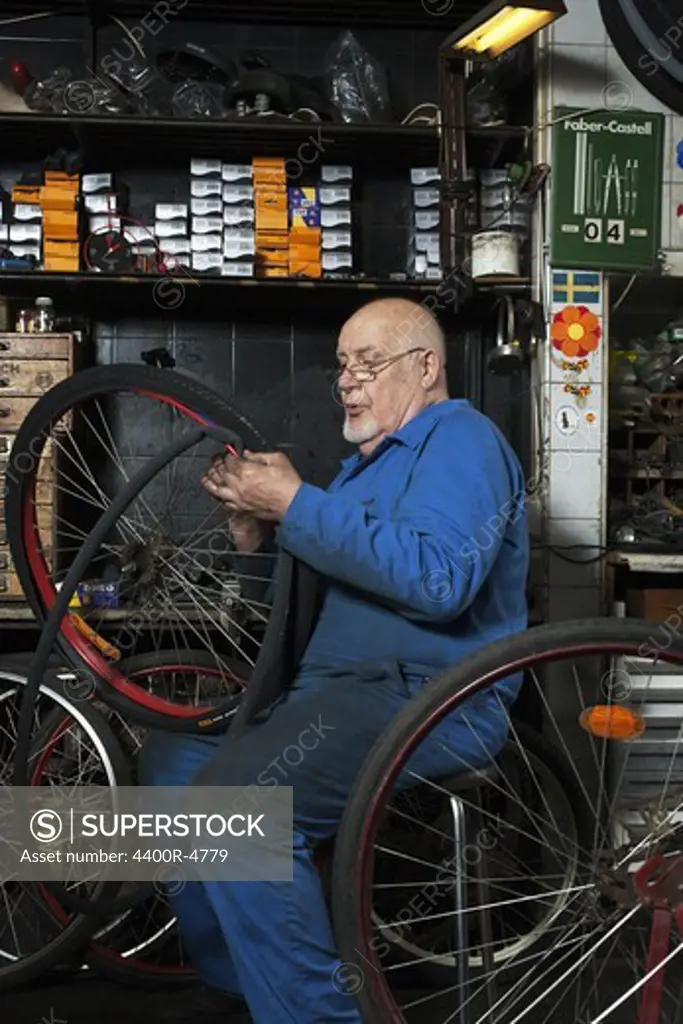 Senior man repairing tire at repairing shop