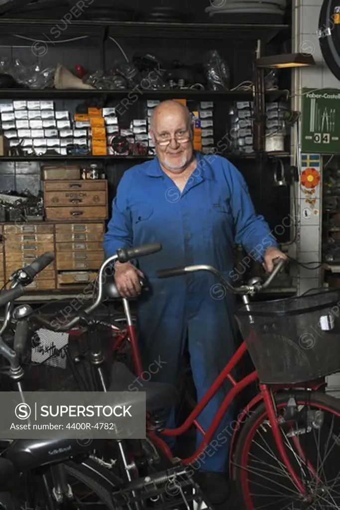 Senior man standing in repair shop, smiling