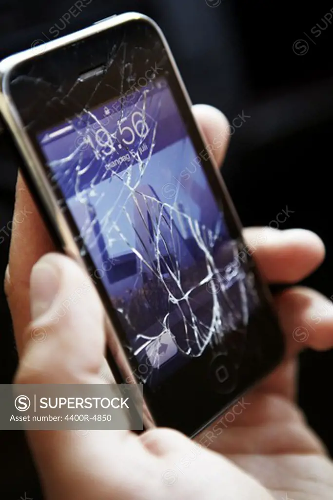 Person holding mobile phone with broken screen