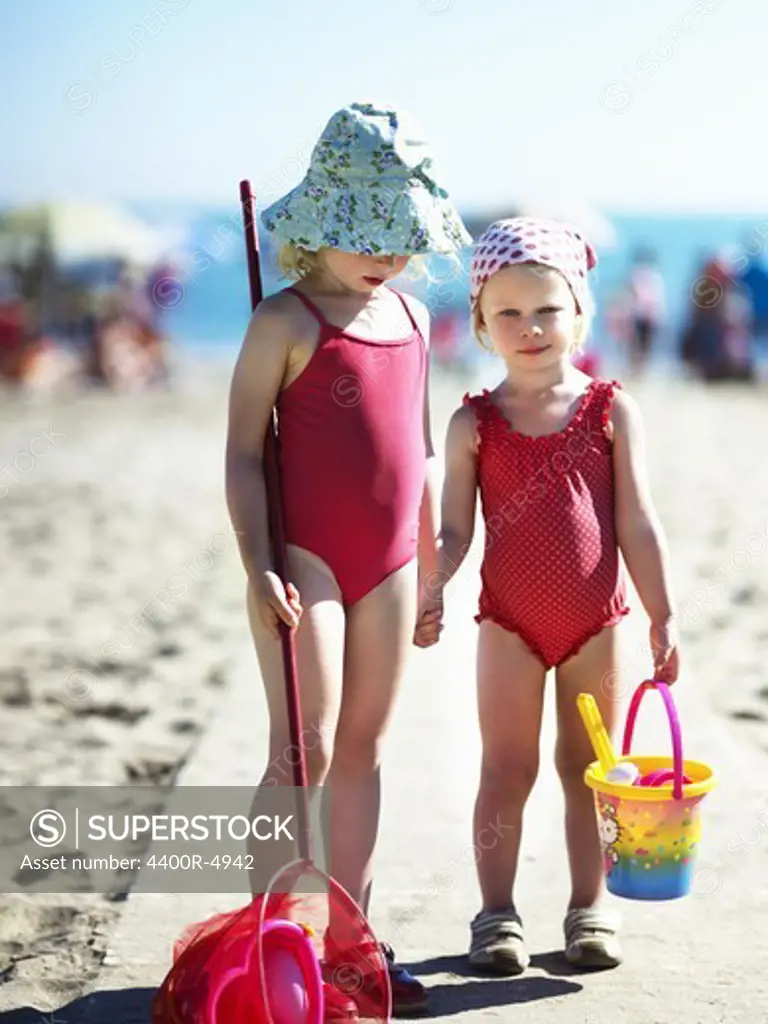Two small girls in read swimming suits on beach