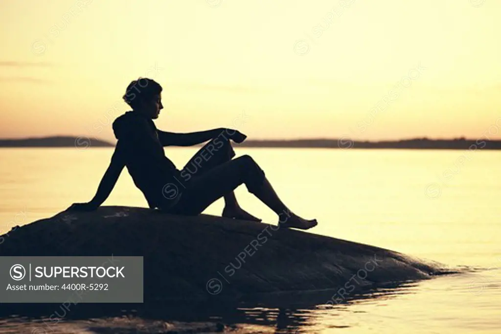 Silhouette of woman at lake at sunset