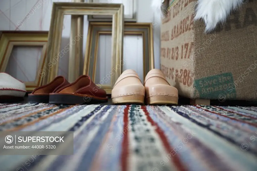 Close up of slippers and clogs on striped carpet