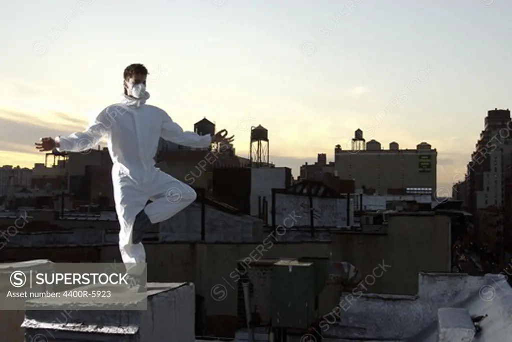 A man wearing protective clothing, standing on a roof in New York City, USA.
