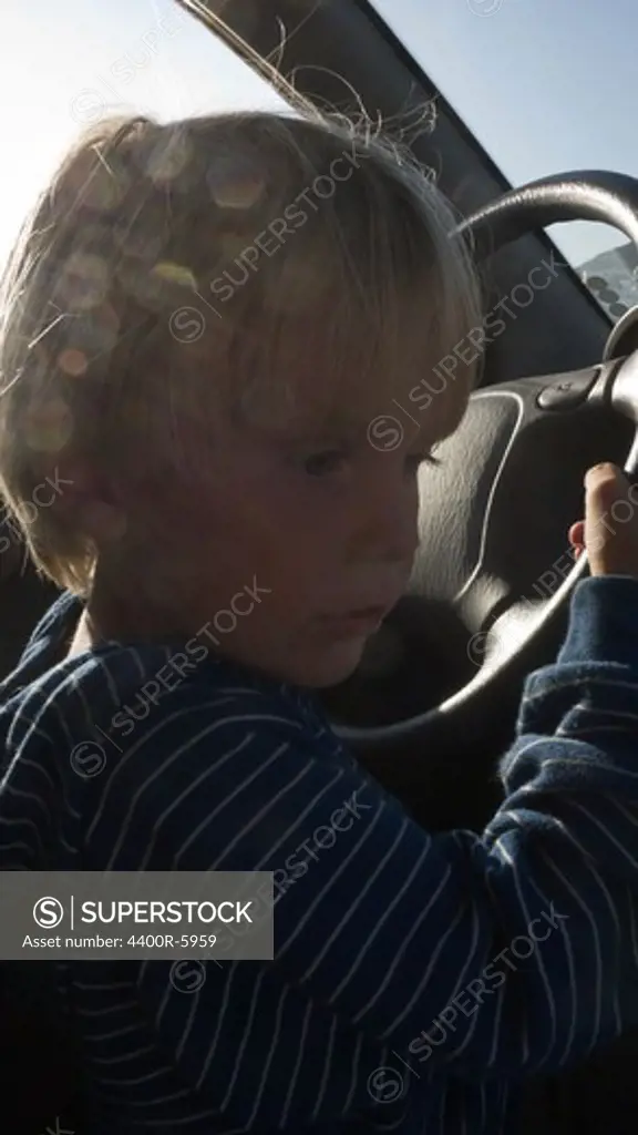 Boy driving a car, Amorgos, Greece.