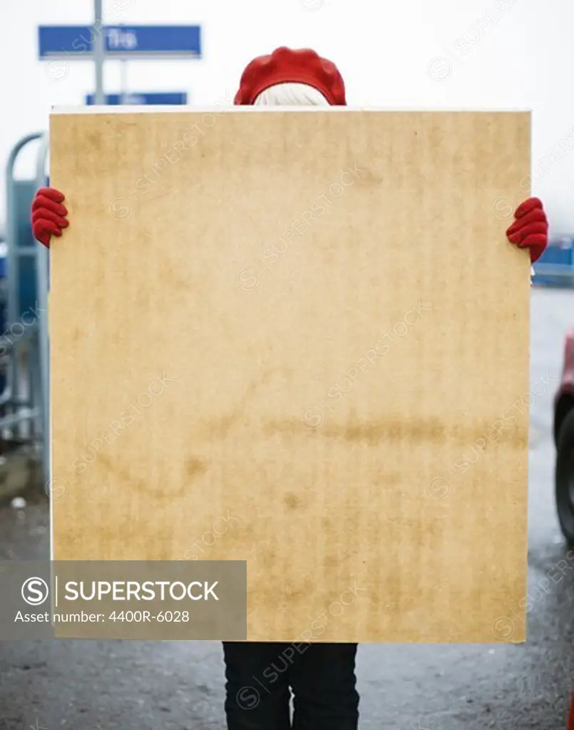 A woman behind a sheet of plywood, Sweden.