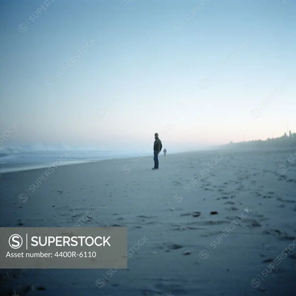 A man standing on a beach, New Jersey, USA.
