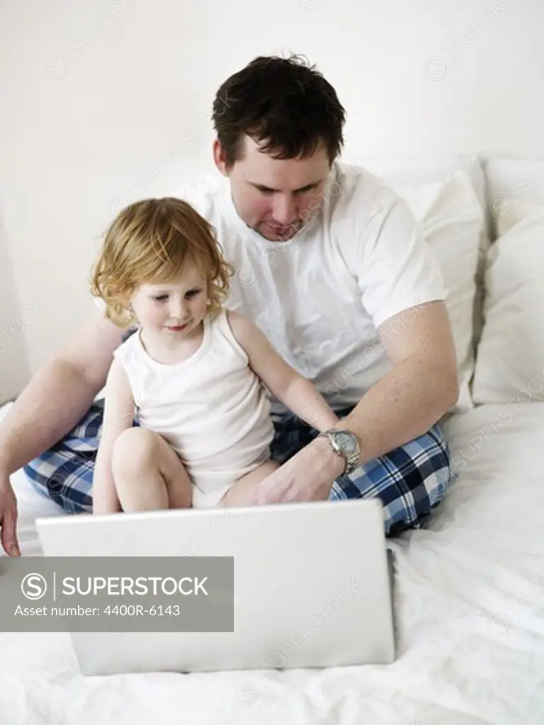 Father and daughter in front of a laptop, Sweden.