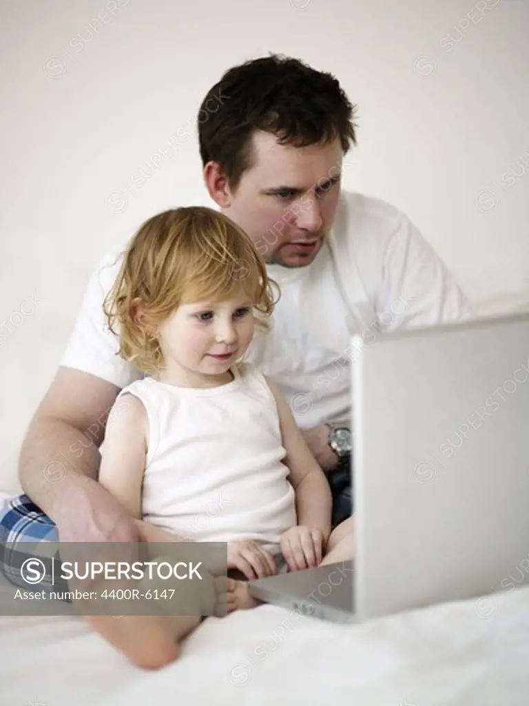 Father and daughter in front of a laptop, Sweden.