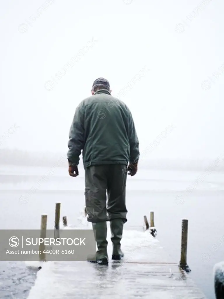 An old man walking on a jetty, Sweden.